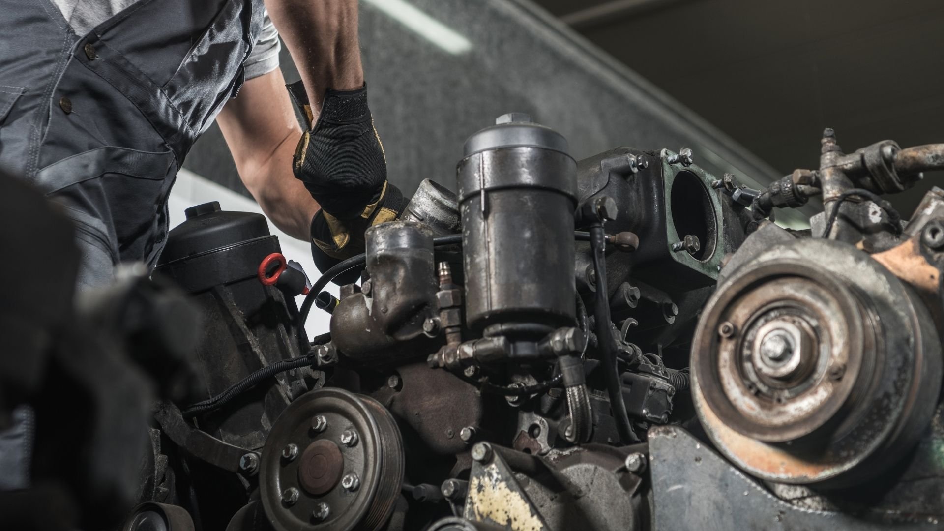 Mechanic in black gloves works on car engine components in garage